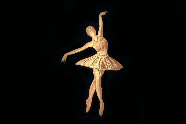 Gold textured silhouette of a ballerina in a classic pose on black